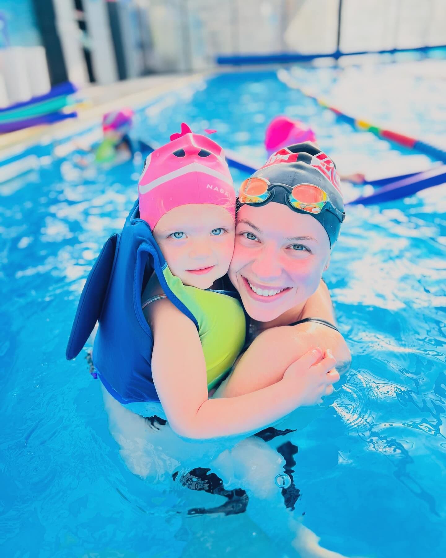 Instructoare Happy Swim ținând în brațe un copil zâmbitor, în bazin